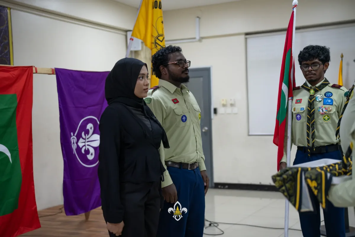 Two new members stand beside a flag bearer before their Rover investiture.