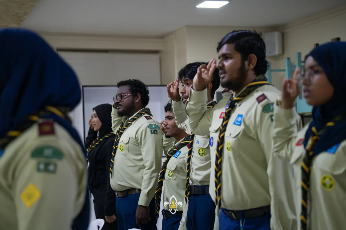 A side view of Rovers and leaders giving the Scout salute.